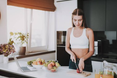 Atletik kız mutfakta duruyor. Pişirme kavramı... Sağlıklı bir yaşam tarzı. Genç ve yakışıklı. Spor vücut. Evin iç. Meyve ve sebze. Sabah taze besin. Rol modeli. Vitamons tablo.
