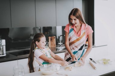 Genç aile mutfak At hamur ile yemek pişiriyor. Mutlu aile ilişkisi var. Birlikte yemek yapmak. Önlük giymek. Aktif tatil eğlence. Dışarı hamur rulo. Pişirme için bilgi edinin. Anne ve kızı.