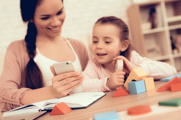 Menina feliz e mãe olhando no telefone em casa . — Fotografia de Stock