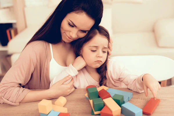 Мама и грустный ребенок собирают кубики на столе дома — стоковое фото