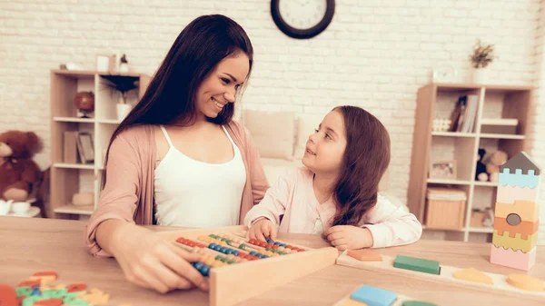 Mulher feliz com jogo de tabuleiro ensina criança em casa . — Fotografia de Stock