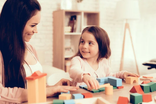 Усміхнені мама і дочка грають кубики на столі . — стокове фото