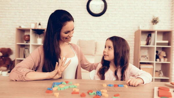 Mulher e menina com números de brinquedo coloridos na tabela . — Fotografia de Stock