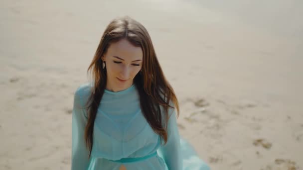 Sexy dziewczyna w piękny sukienka spacery wzdłuż plaży i patrzy w aparat — Wideo stockowe