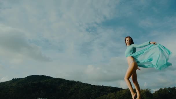 Irl i en bikini med nakna sexiga ben rör sig mot himlen och vidrör hennes klänning — Stockvideo