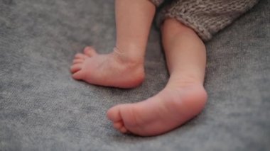 Yenidoğan ayakları. Vücut parçalarına yakın çekim. Gri bir battaniyeye karşı bebeğin ayakları.