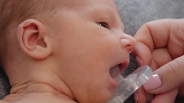 Newborn baby sucks a baby's dummy. Weaning from the breast. — Stock Video