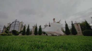 Beyaz elbiseli güzel genç kız çimlerin üzerinde dönüyor ve dans ediyor.