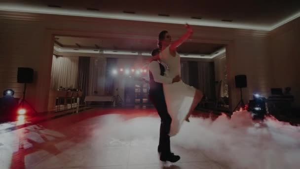 Tanec páru v reflektorech a obklopen mlhou a plíživým kouřem — Stock video