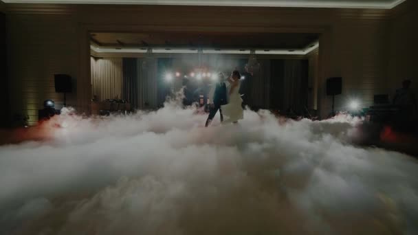 Танець пари в прожекторах і оточений туманом і повзучим димом — стокове відео