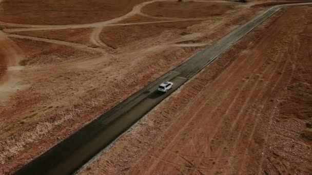 Samochód przejeżdża przez pustynię pustą, opuszczoną autostradą do morza. Antena — Wideo stockowe
