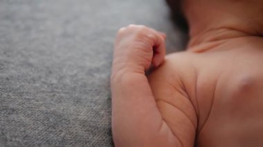 Gri arka planda yeni doğmuş bir bebeğin bebek elinin yakın çekimi. Vücudun bir parçası.