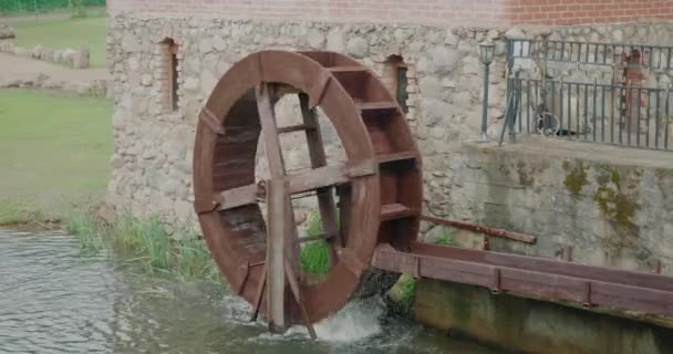 Een houten waterrad van een watermolen. De stroming van het water draait het wiel — Stockvideo