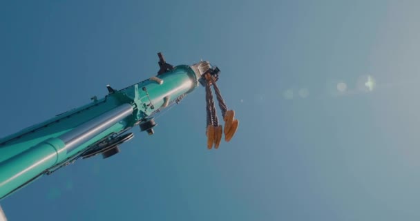 Primer plano de la pluma de la grúa del camión móvil y el auge en el fondo del cielo azul. Brazo de grúa con cadenas y gancho. — Vídeo de stock