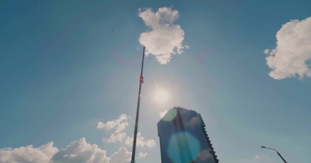 Панорамный широкоугольный снимок мобильного грузового крана с полностью удлиненной стрелой перед небоскребом. Крупнейший мобильный кран — стоковое видео