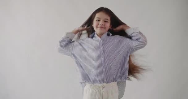 Feliz alegre menina de cabelos compridos salta e joga seu cabelo alegremente. Isolados . — Vídeo de Stock