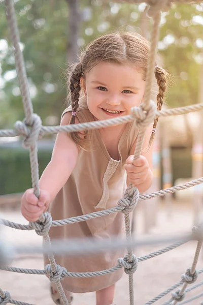 3 yaşındaki Mutlu Kız oyun parkında oynuyor. Çocuk ip merdivene tırmandı..