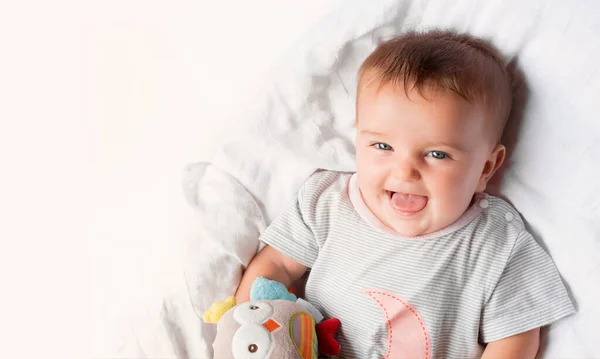 Mutlu 6 aylık bebek beyaz arka planda bir oyuncakla oynuyor..
