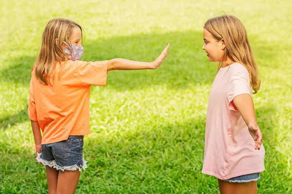 Kız arkadaşını kucaklamak için maskesiz koşar. Maskeli ikinci kız durduğunu gösteriyor. Sosyal mesafeler. salgın COVID-19.