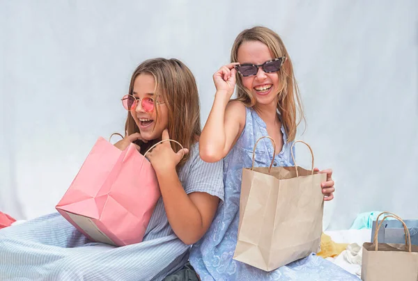 girls with glasses laugh.  Children sort out shopping bags after shopping