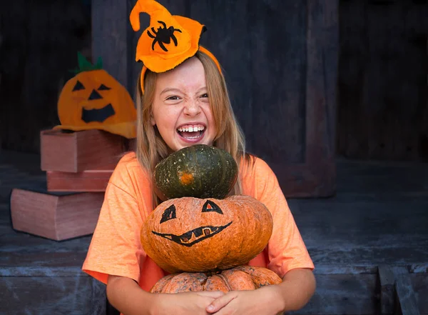 Balkabağı tutan mutlu kız çocuğu tahta cadılar bayramı arka planında