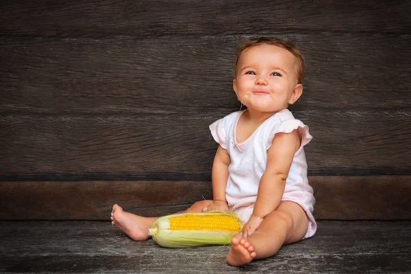 Pequena Menina Bonito Senta Fundo Madeira Escura Mastiga Seda Milho — Fotografia de Stock