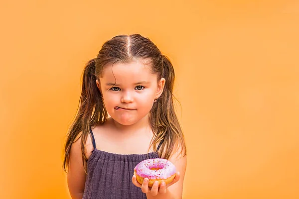 Çocuk Kızın Elinde Pembe Bir Çörek Tutuyordu Sarı Arkaplanda — Stok fotoğraf