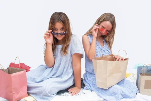 girls with sunglasses.  Children sort out shopping bags after shopping