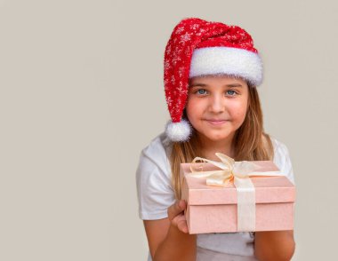 Noel Baba şapkalı çocuk Noel hediyeli kutuyu uzatıyor.