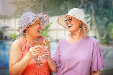 Son sınıftaki kadınlar dışarıda havuz kenarında şarap içiyorlar.