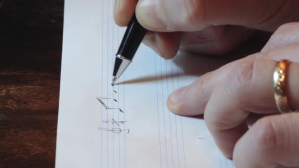 作曲家は ペンの手をクローズアップしてシート上の音楽ノートを書く — ストック動画
