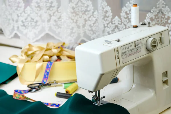 テーブルの上にミシン 前景に緑の布 コンセプト 趣味で縫製 — ストック写真