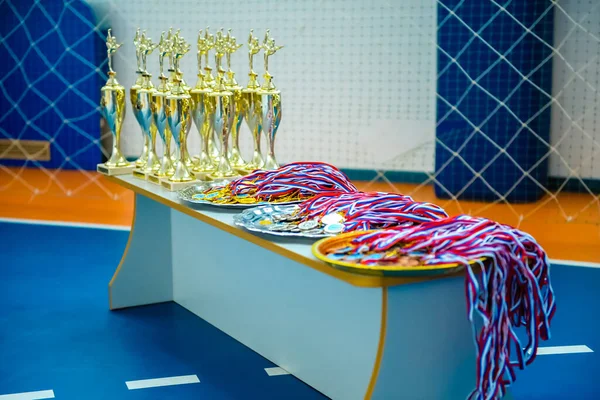 Medals and cups are on the table to award winners in children\'s artistic gymnastics competitions. Medals out of focus.