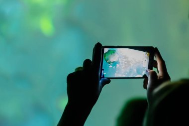 Bir adam akvaryumdaki performansın videosunu cep telefonuyla kaydediyor.