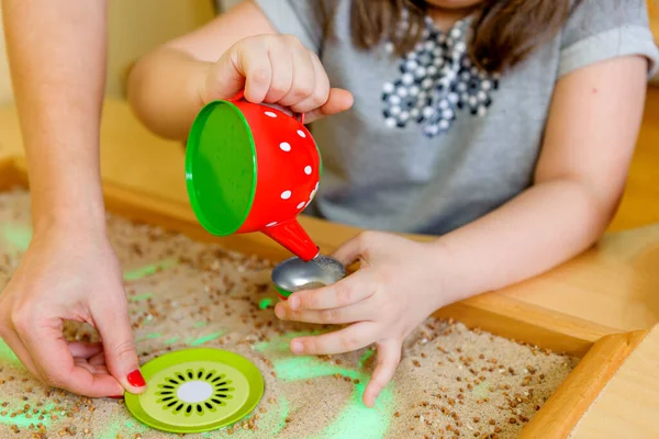 Handikappad Flicka Leker Med Sand Och Vattenkokare Vuxen Hjälper Stockbild