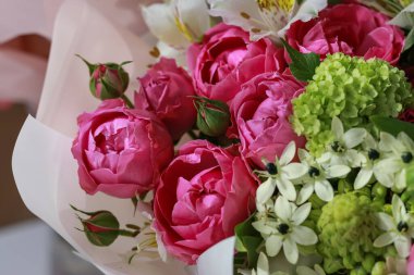 Pembe-yeşil gül buketi, beyaz zambaklar, mor arka planda ortancalar