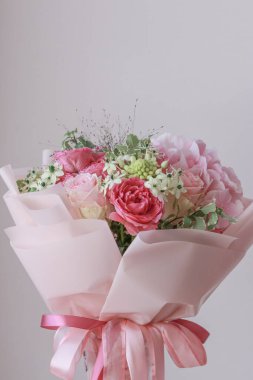 Pembe gül buketi, ortanca, yeşil okaliptüs yaprakları açık arkaplanda.