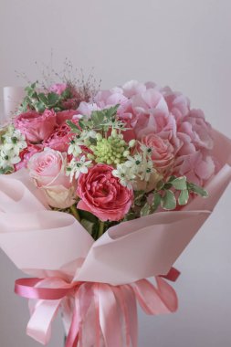 Pembe gül buketi, ortanca, yeşil okaliptüs yaprakları açık arkaplanda.