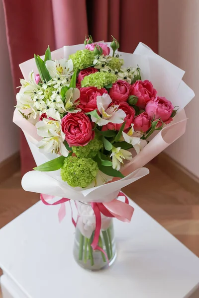 Pink-green bouquet of roses, white lilies, hydrangeas on a light background