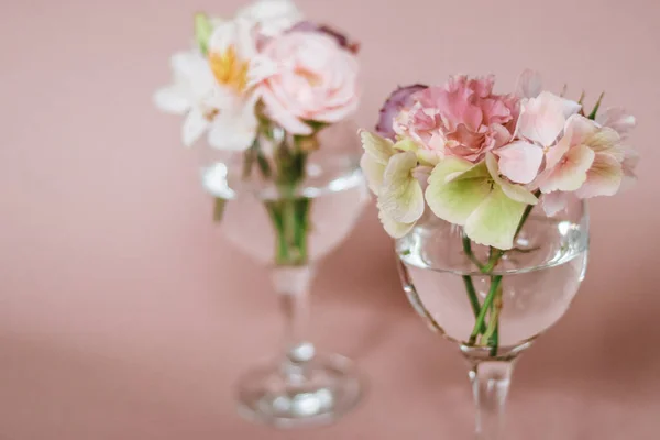 Cut flowers in glasses of water. Mini composition for table decoration.
