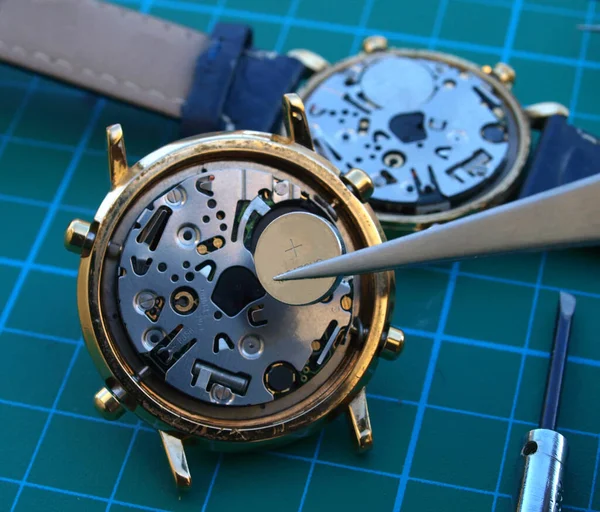 watchmaker replacing watch battery, close up of battery and quartz watch caliber