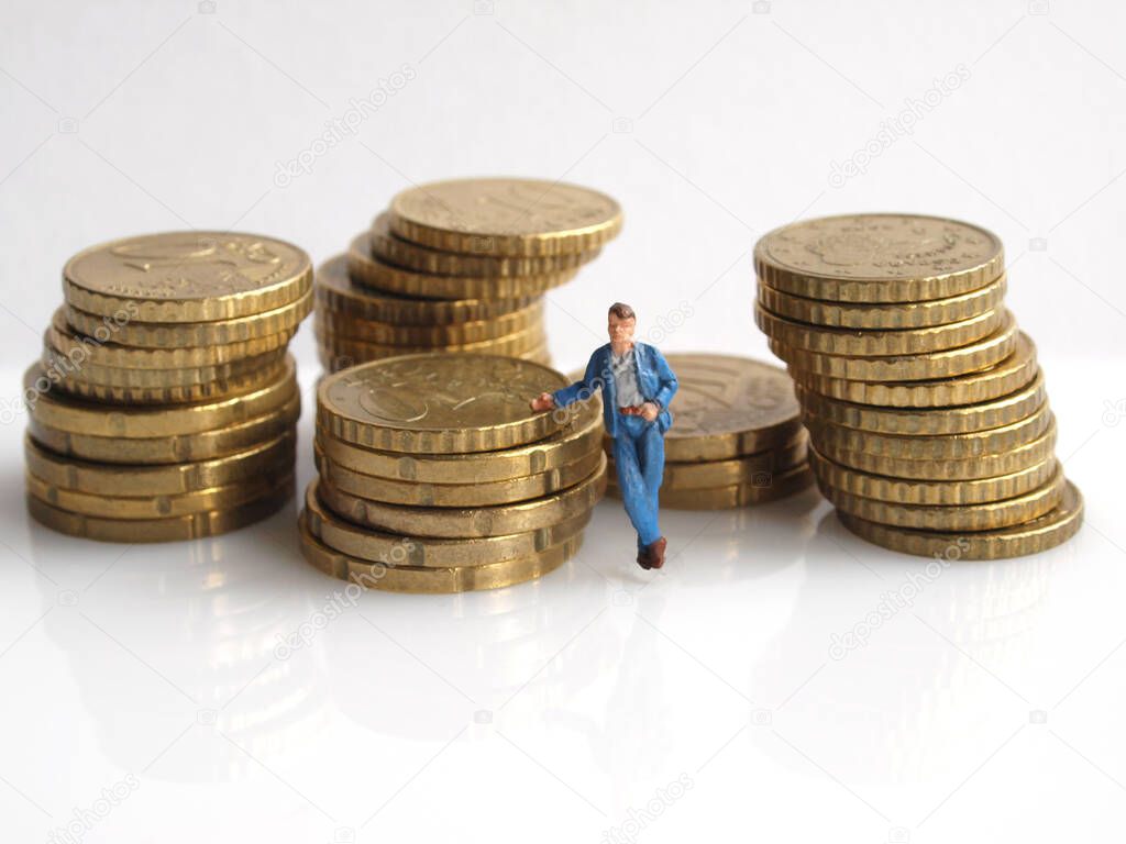 miniature toy of bussiness man next to stacks of coins, bussiness success allegory