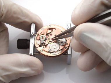 Saatçi eski saat hareketini tamir ediyor
