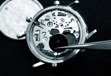 watchmaker change battery, close up of battery and quartz watch caliber in the background monochrome in blue image clipart