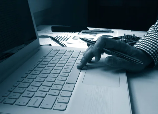 finance market analyst working on laptop with several charts over the white table, monochrome image