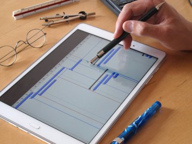 Projenin proje zaman tablosu çizelgesinde tablet bilgisayarı üzerinde çalışan mühendis