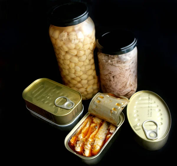 non-perishable food cans over black background
