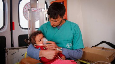 Halep, Suriye 12 Mart 2020 Bir hemşire bir çocuğu kucakladı ve onu ambulansın içinde tedavi etti