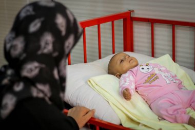 Halep, Suriye 01 Mart 2020: Bir anne hasta çocuğunun yatağında uzanan elini tutuyor. Sevimli yeni doğmuş bebek kuvöz bakım hastanesinde uyuyor..
