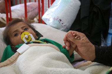 Halep, Suriye 01 Mart 2020: Bir anne hasta çocuğunun yatağında uzanan elini tutuyor. Sevimli yeni doğmuş bebek kuvöz bakım hastanesinde uyuyor..